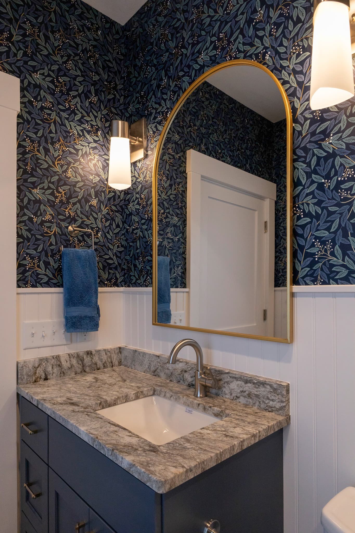 Powder room with botanical wallpaper and gold-framed mirror