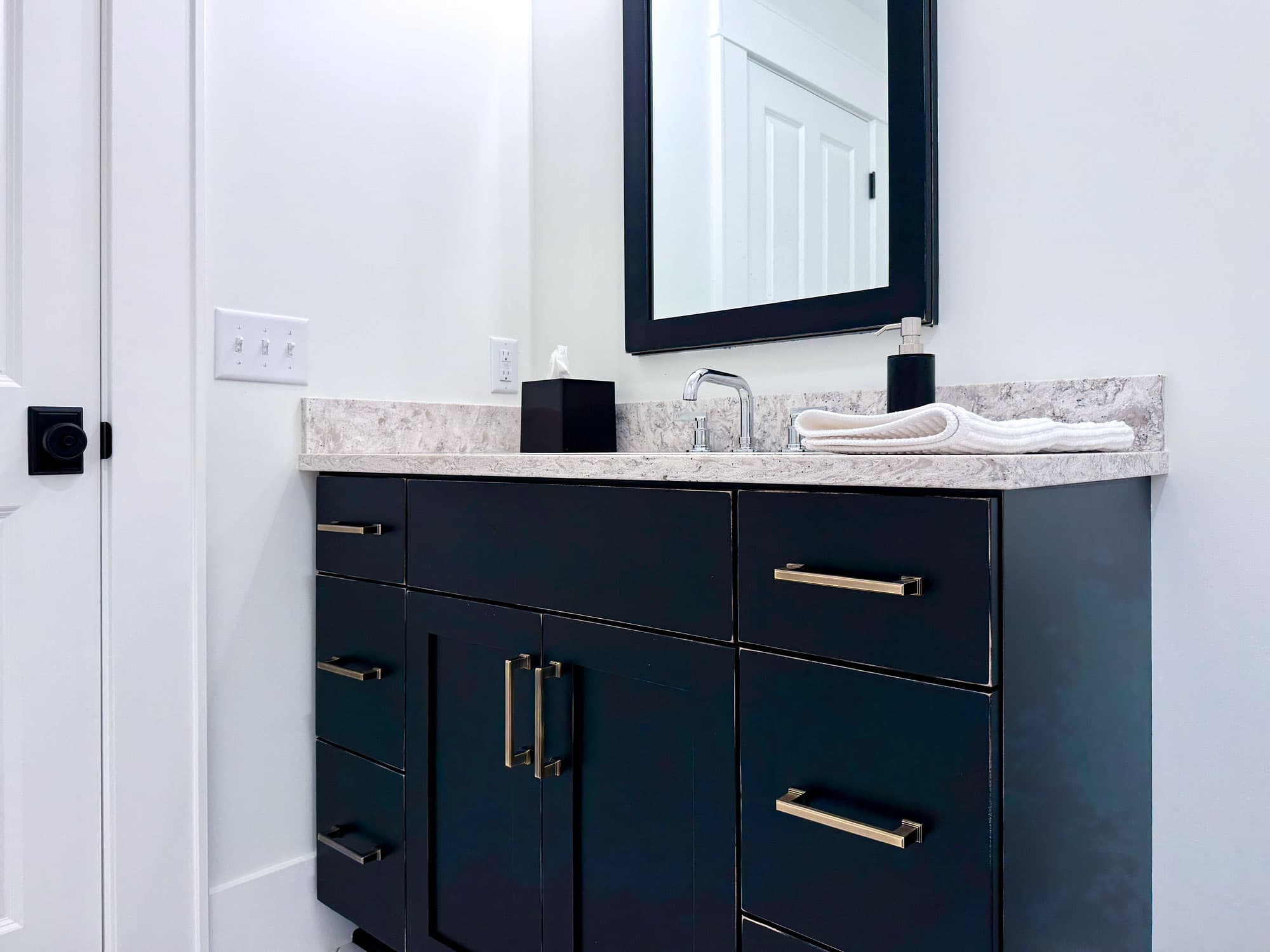 Navy vanity with stone countertop and brushed brass hardware