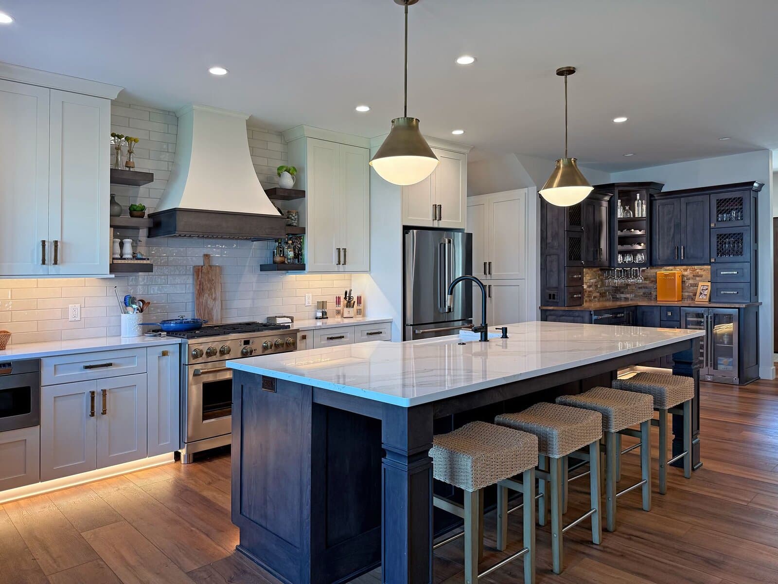 Custom kitchen with dark island, white cabinets, and pendant lighting