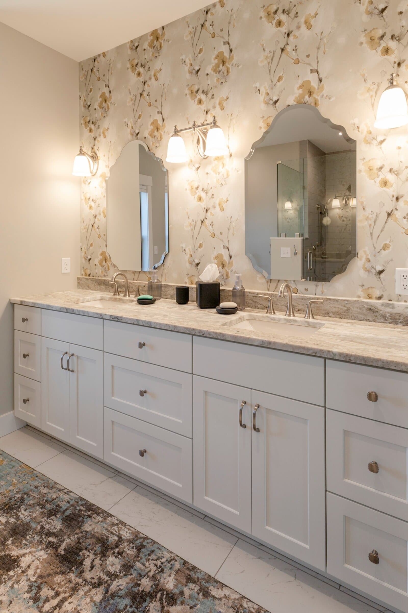 Master bath with double vanity, floral wallpaper, and marble countertop