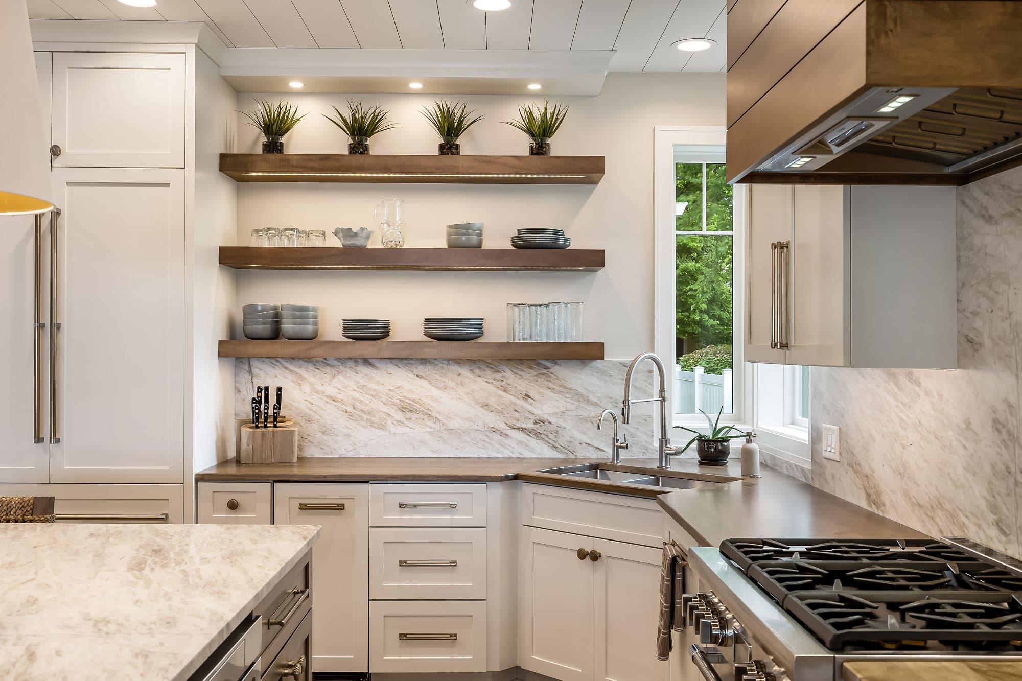 Kitchen with open floating shelves, wood countertops, and marble wall