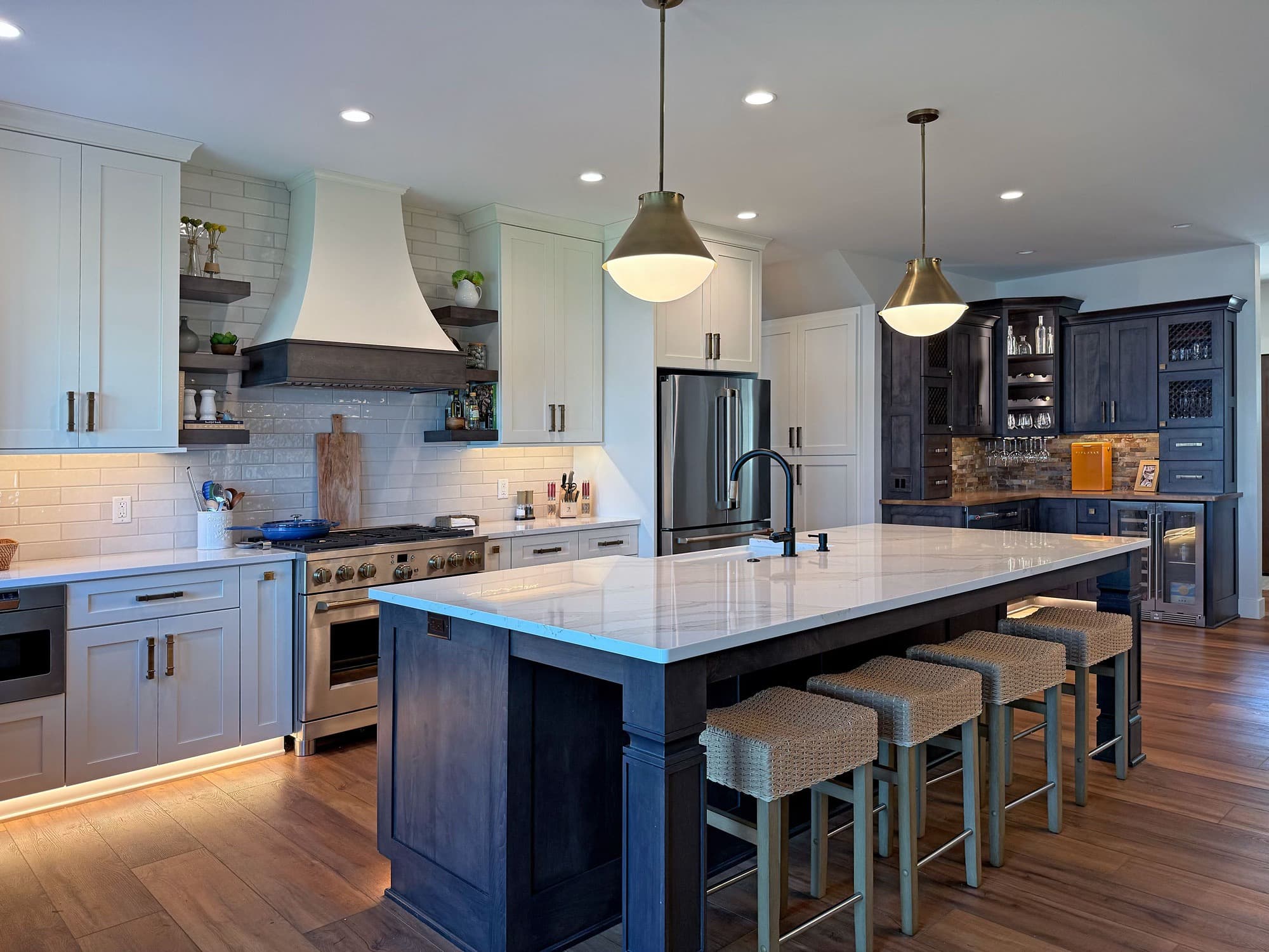 Custom kitchen with dark island, white cabinets, and pendant lighting