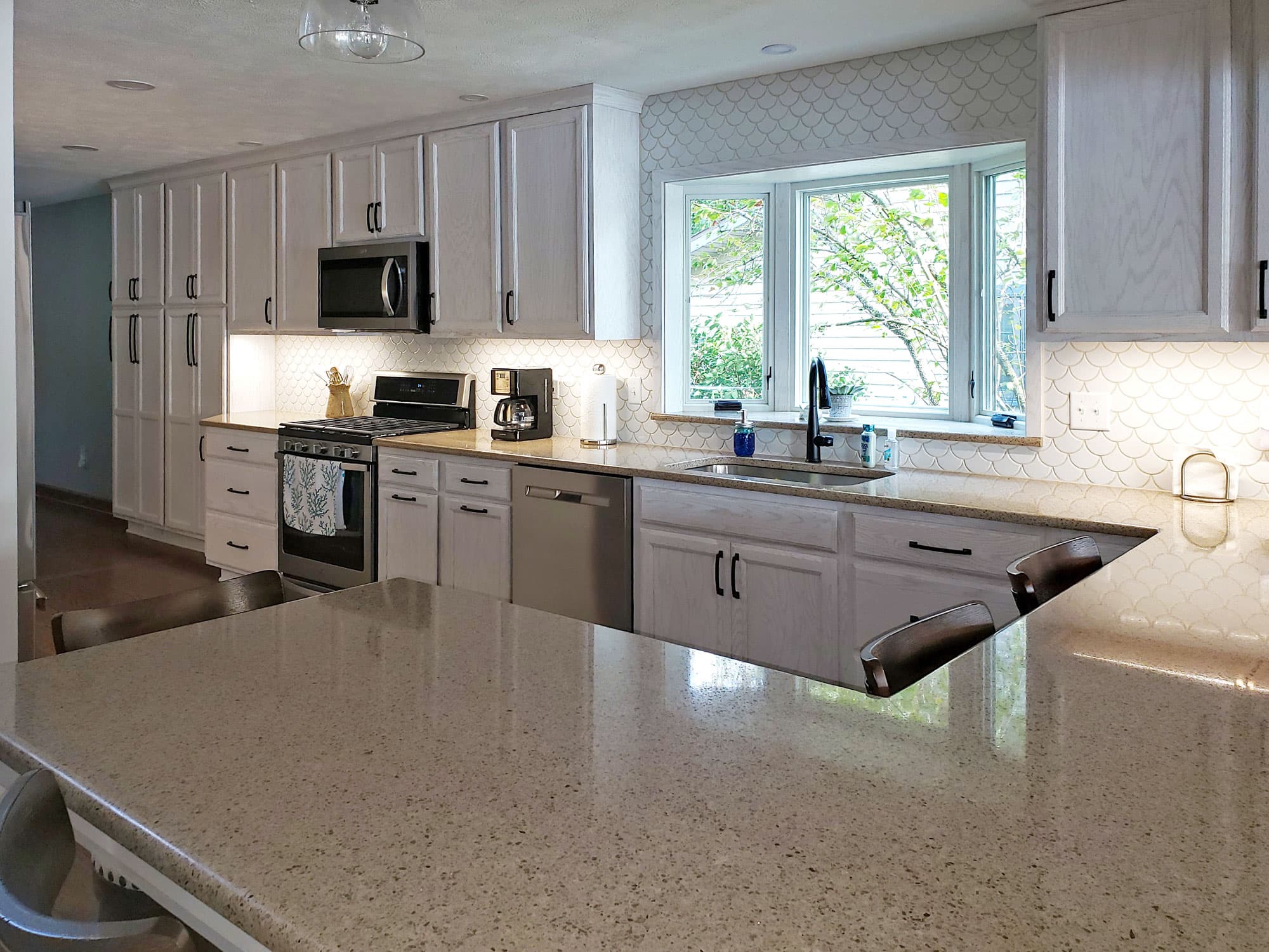 Light grey kitchen with quartz peninsula and arabesque tile backsplash