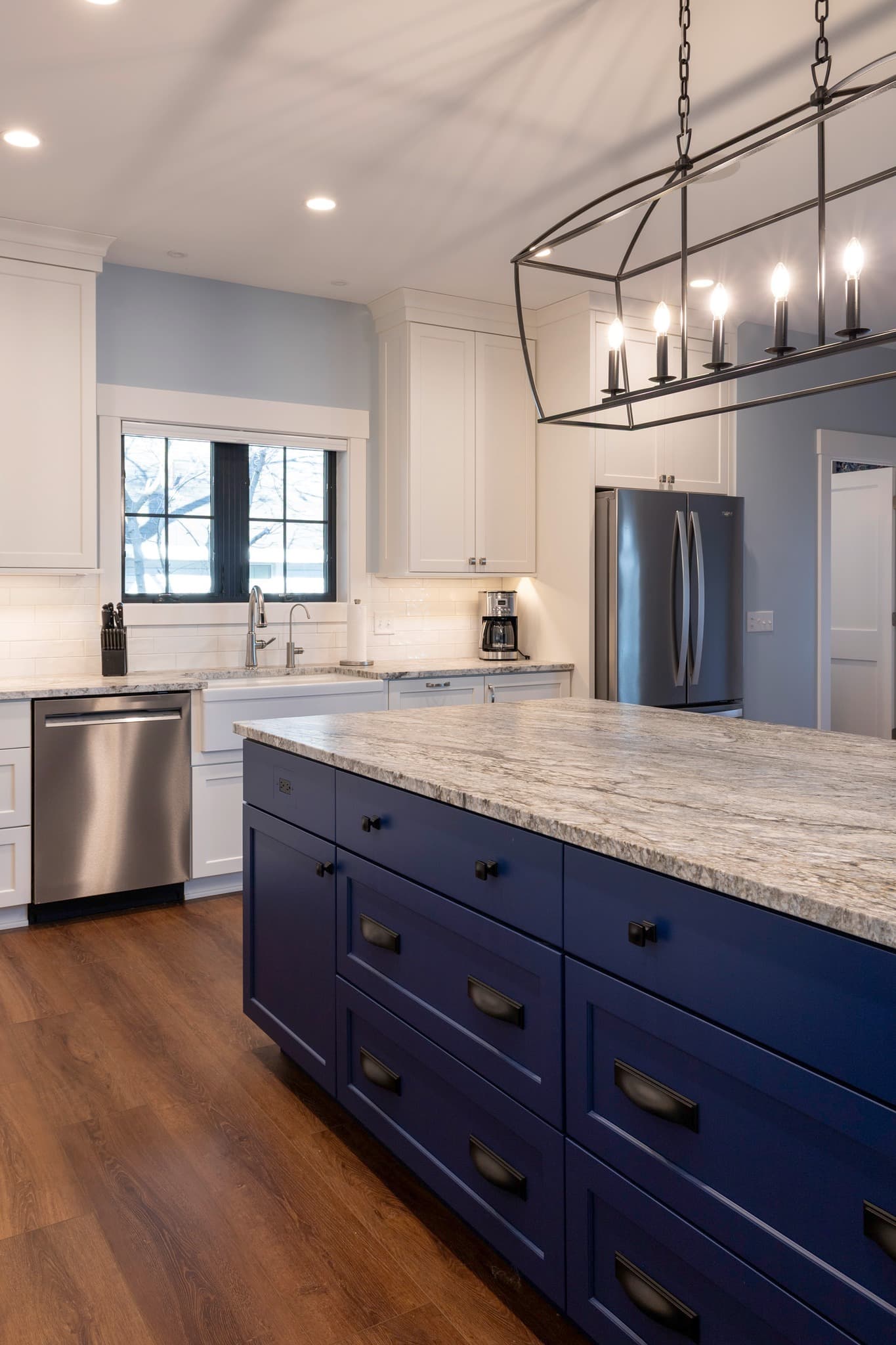 Navy island with granite countertop and iron cage chandelier