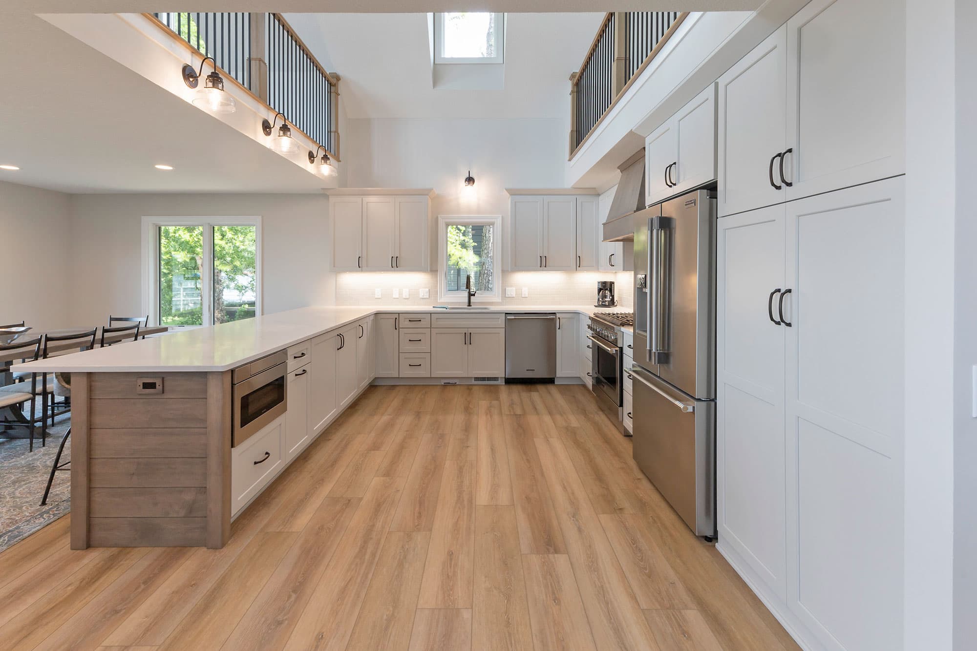 Open-concept kitchen with loft railing, white cabinets, and wood island