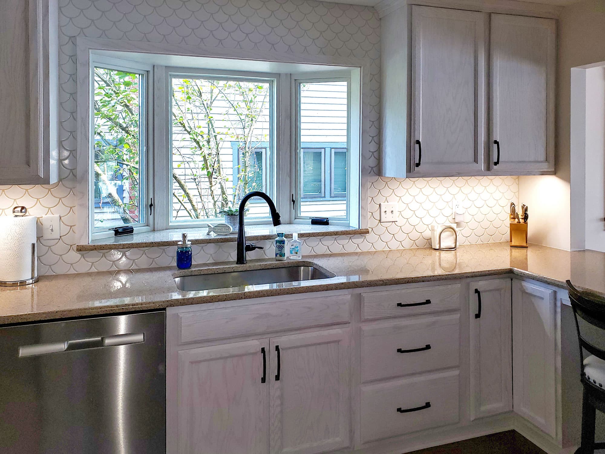 White kitchen with scallop tile backsplash and bay window over sink