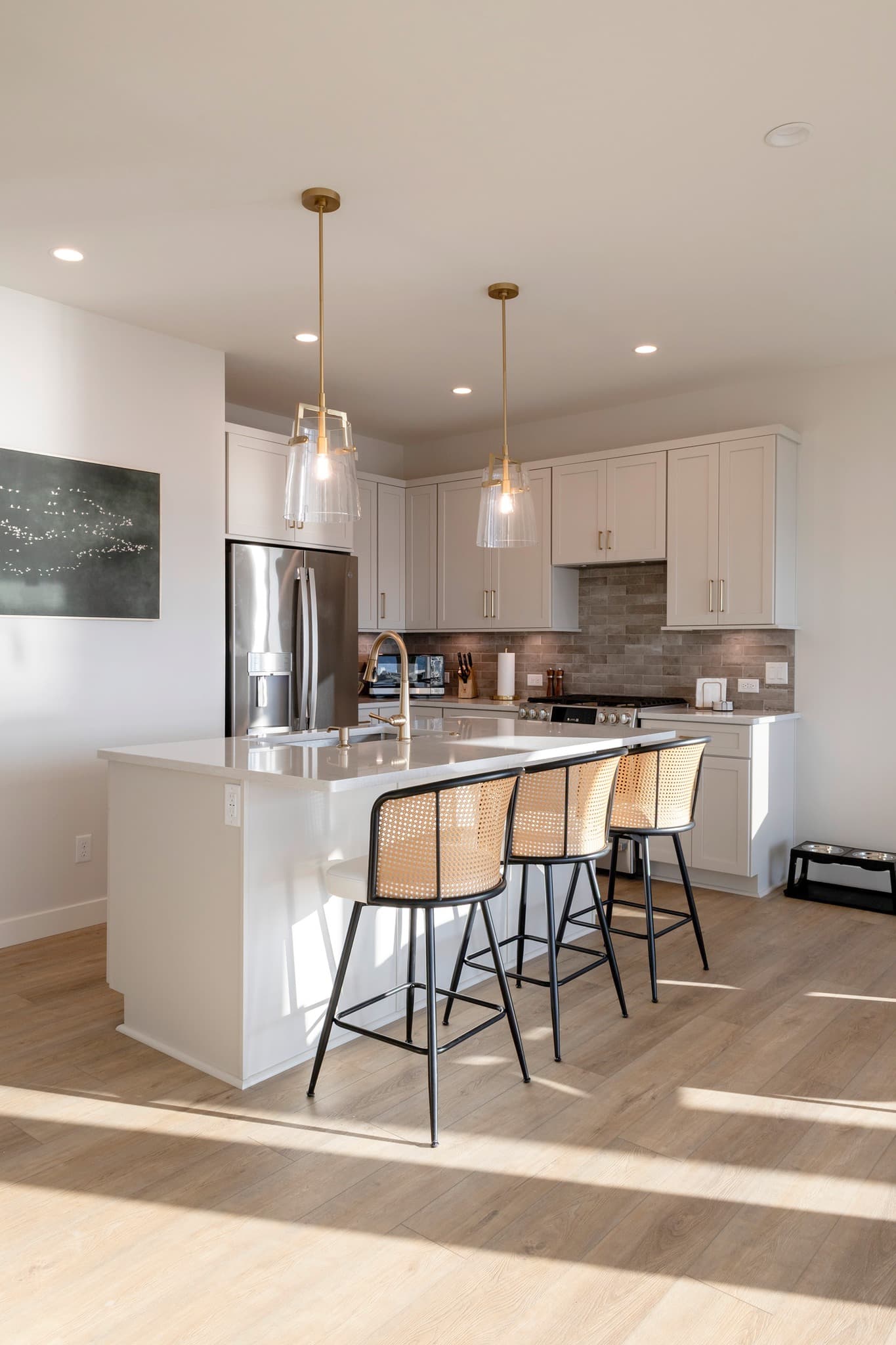 White kitchen with peninsula seating, brick backsplash, and glass pendants