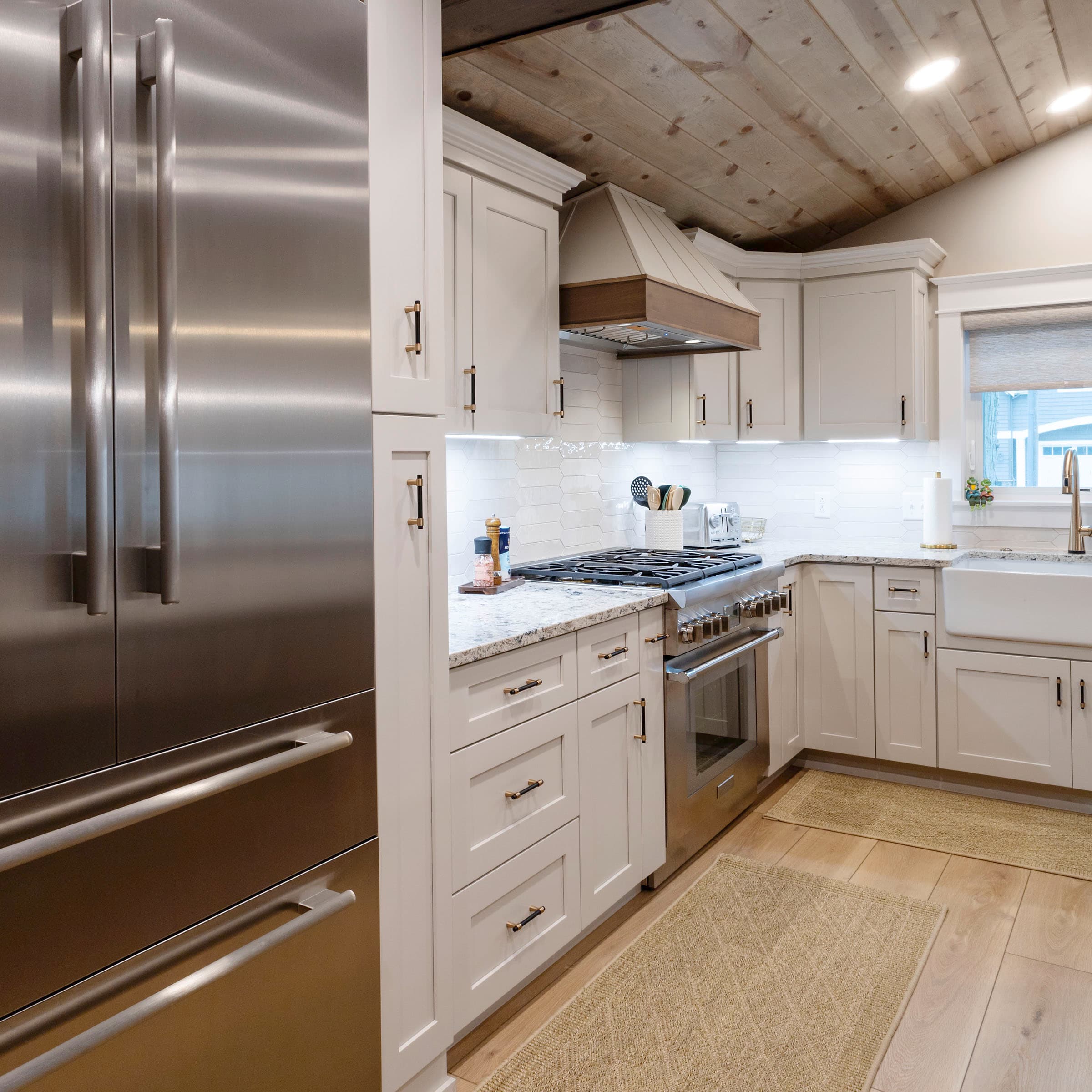 White kitchen with wood-accented range hood and stainless appliances